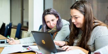 students sat at a desk looking at a chromebook