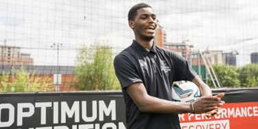 sport student holding a football clapping on a 5 a side pitch