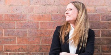 staff member stood in front of a red brick wall