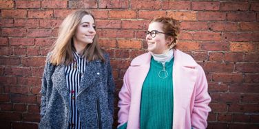 two people in front of a red brick wall