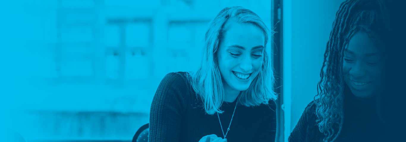 students looking down smiling at book, blue overlay