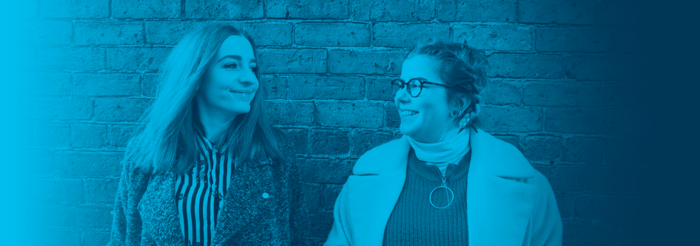 two people in front of a red brick wall with a blue gradient over the top