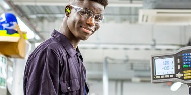 Student in overalls in an engineering bay