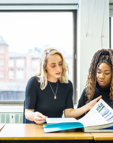 Two Travel And Tourism Management looking at travel brochure