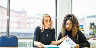 Two Travel And Tourism Management looking at travel brochure