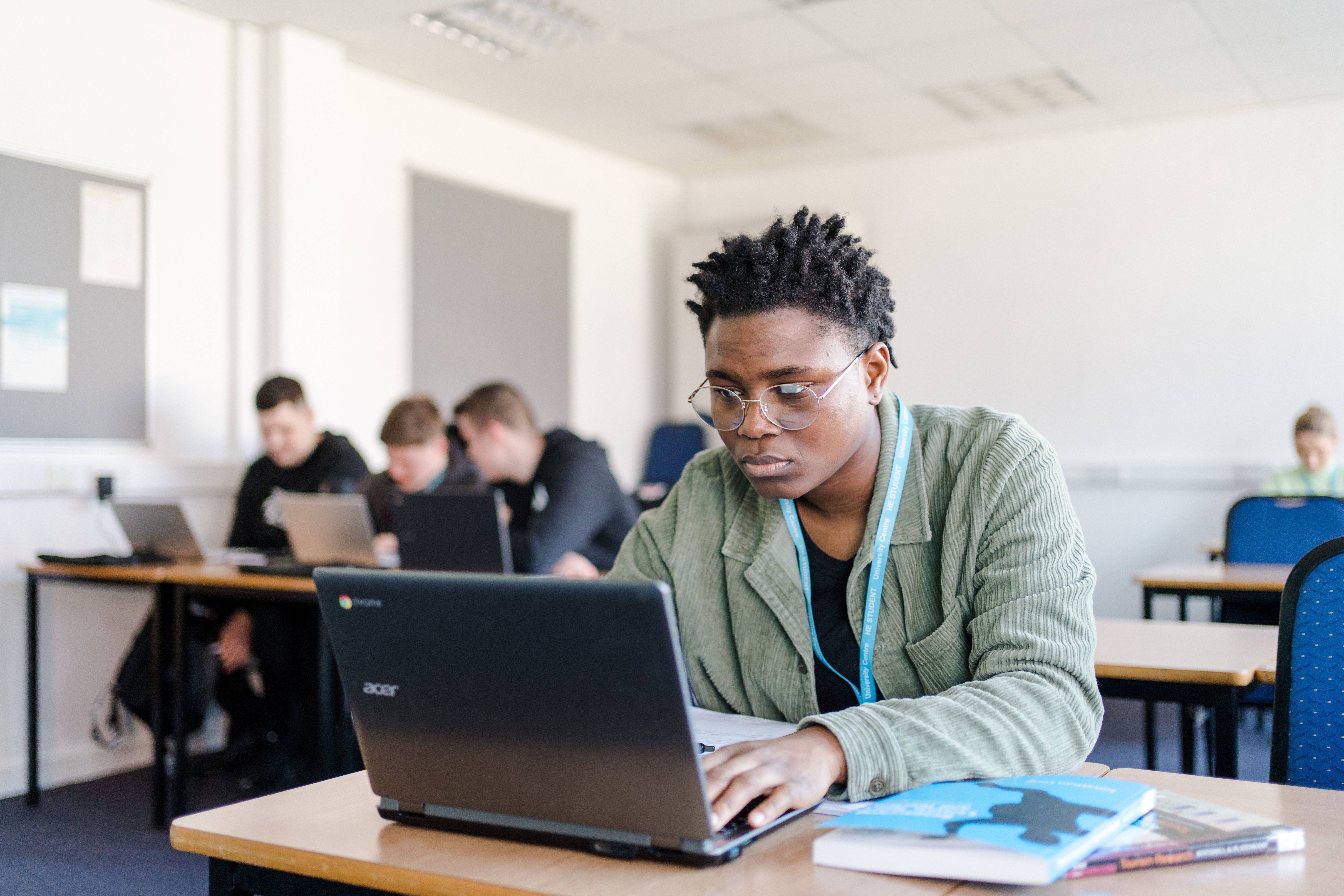 University Centre Leeds student sat at a desk typing on to a Chromebook