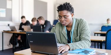 University Centre Leeds student sat at a desk typing on to a Chromebook