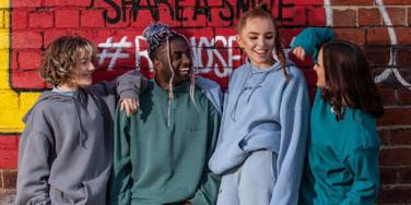 four students stood in front of a graffitied wall