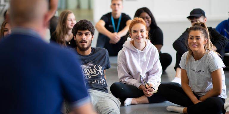 Group of student sit on the floor facing a tutor